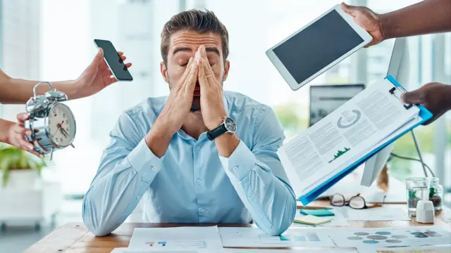 Trabajador con expresión y gestos de estrés abrumado en su despacho susceptible de tratamiento con acupuntura